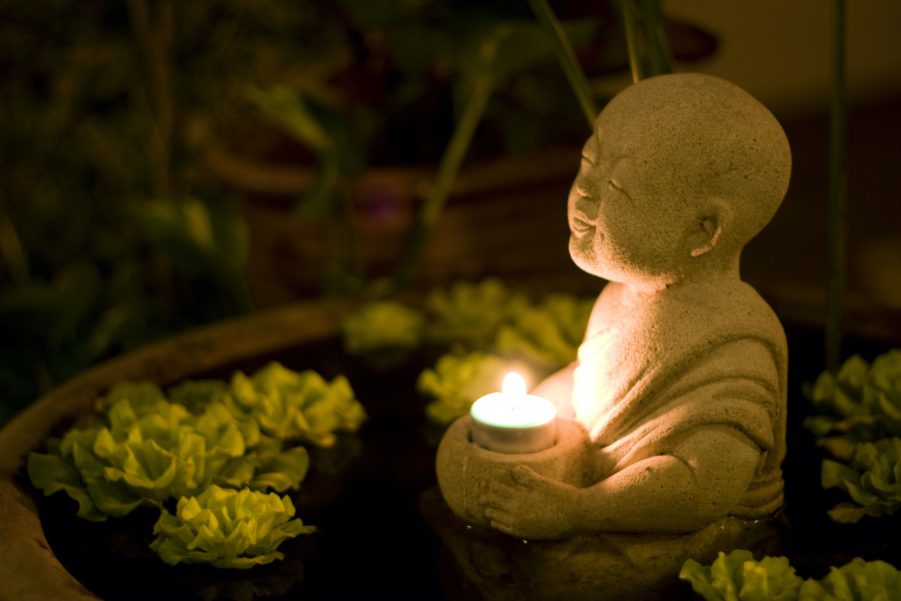 Buddha holding a lit tea candle