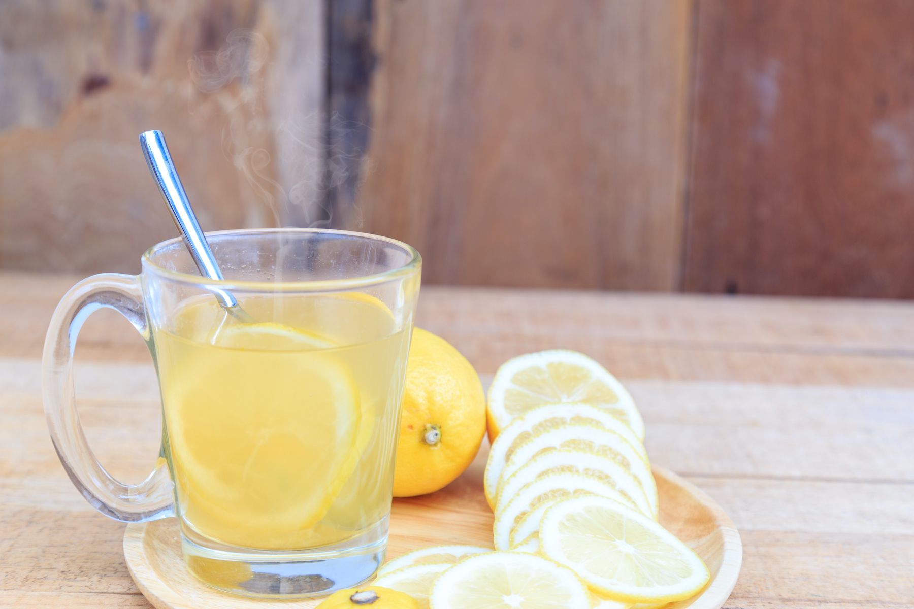 Cup of lemon water on a plate of sliced lemons