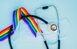 Stethoscope and LGBT rainbow ribbon pride symbol. Blue background