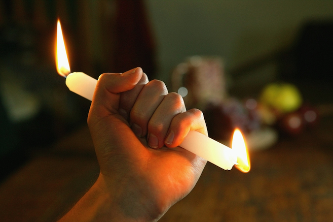 Person holding candle burning at both ends, close up