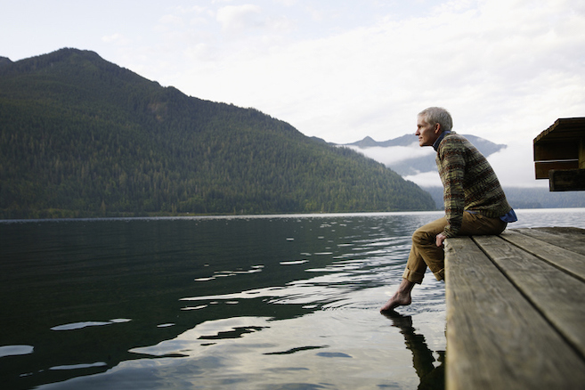 Man sitting on edge of dock with feet in water