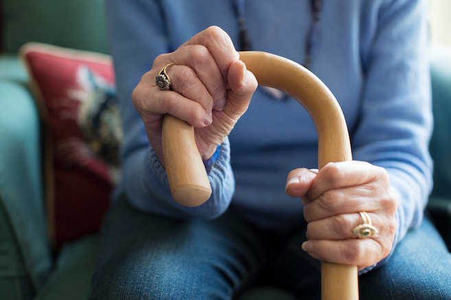 Close up of an elderly woman with Multiple sclerosis holding onto a cane