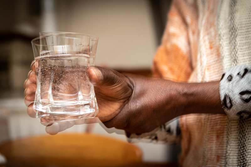 Close up of a woman with parkinson's struggling to hold onto a glass of water