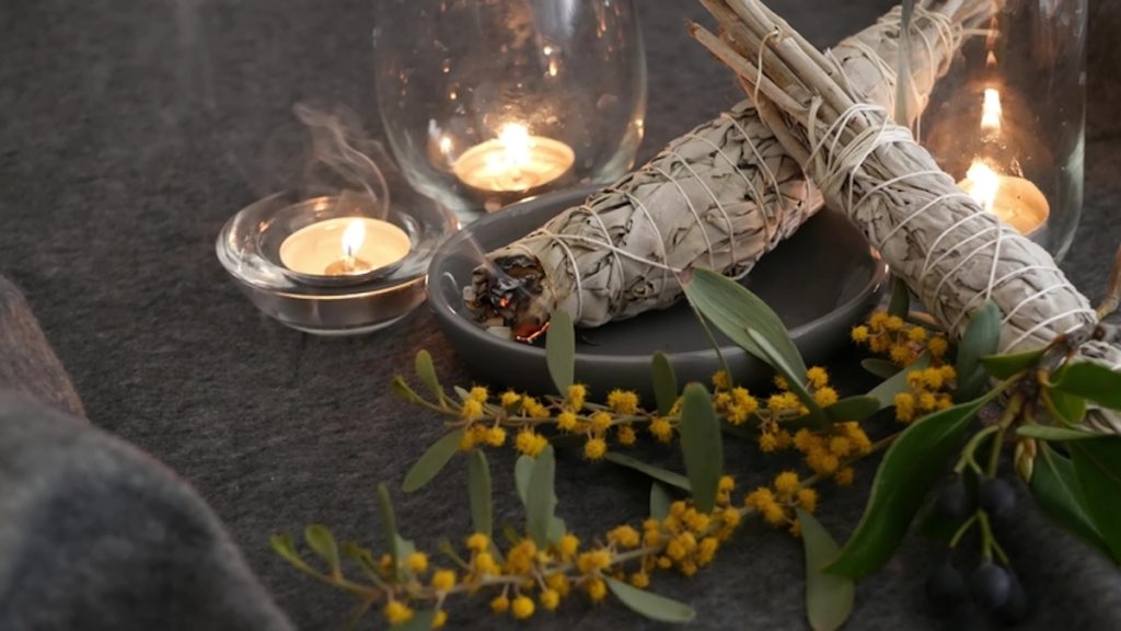 Still life with tea candles, sage sticks on a dark gray background