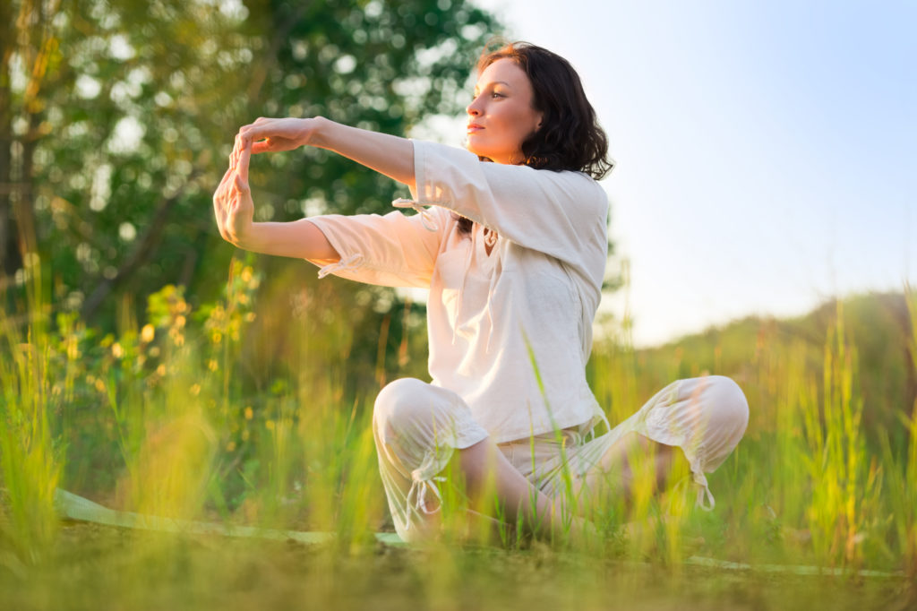 woman doing hand stretches in a sunny field